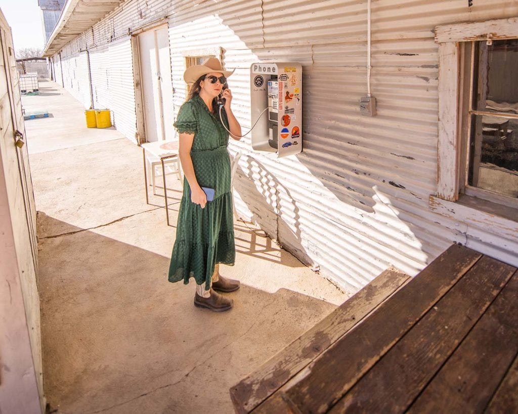 Chelsea Day making a phone call on an old payphone outside the Marfa Spirit Co in West Texas